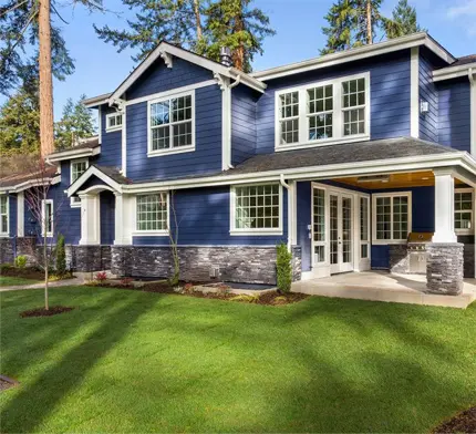 A blue house with white trim and green grass.