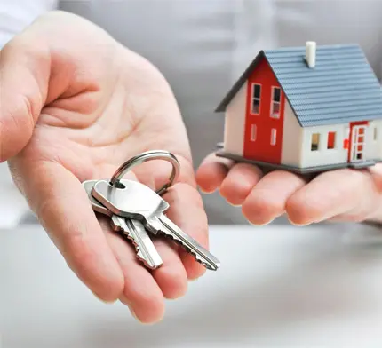 A person holding out their hands with keys in front of them.